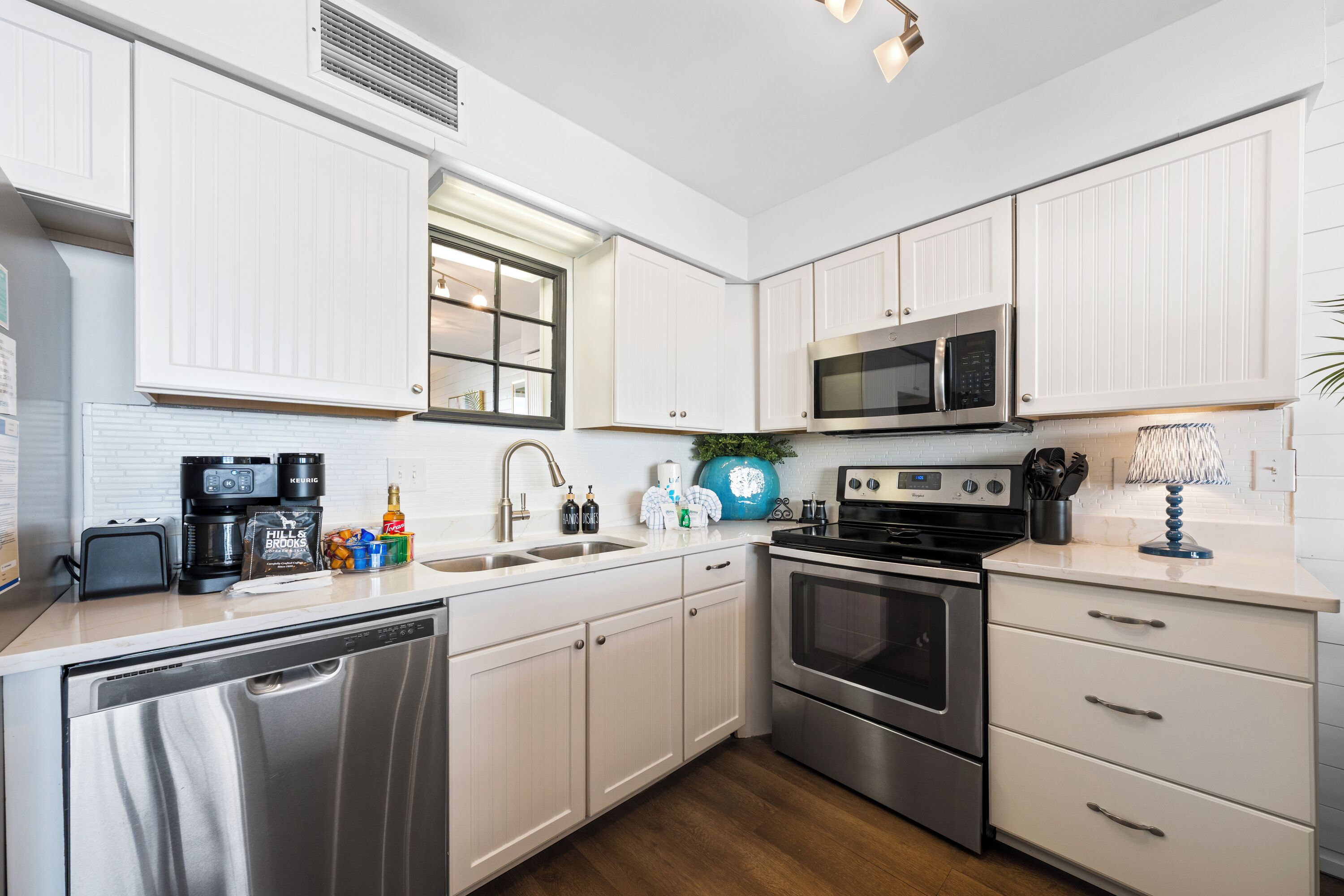 Una cocina moderna con armarios blancos, electrodomésticos de acero inoxidable y lavavajillas integrado.