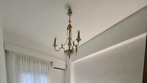Een moderne slaapkamer met een groot bed, nachtkastjes, een kroonluchter en uitzicht op de omgeving.