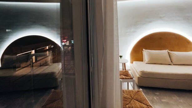 Een moderne hotelkamer met een groot bed, een slaapbank en een wandelement met een gebogen vorm.