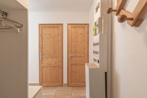 A hallway with two wooden doors, a white wall, and a white cabinet with a small shelf. - Apartment '8 Guests – At the Foot of the Slopes' with Mountain View and Private Terrace (Morillon)