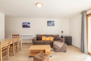 En stue med sofa, sofabord, spisebord med stole og en lampe.