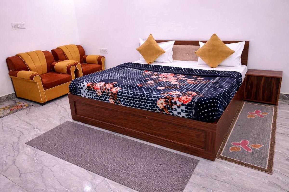 Une chambre à coucher avec un lit en bois, un canapé, une table de chevet et un tapis à motifs.