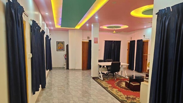 A hotel lobby with a marble floor, a reception desk, and a seating area with a patterned rug.