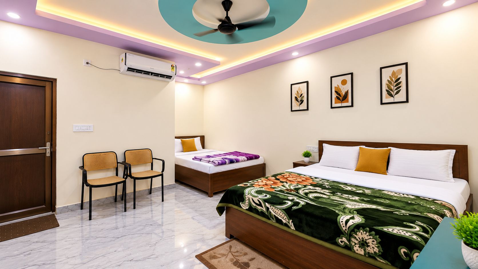 Une chambre d’hôtel comprenant un lit, deux chaises, une table de chevet, un climatiseur fixé au mur et un ventilateur de plafond.