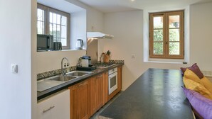 Une cuisine équipée d’un four à micro-ondes, d’une cuisinière, d’un évier et de meubles de rangement en bois.