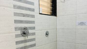 A bathroom with a toilet, a shower, and a bucket.