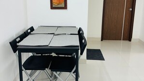 A dining area with a table set for four, a wooden door, and a framed painting on the wall.