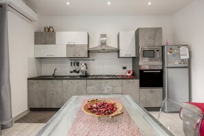 Una cocina moderna con armarios grises, una estufa a gas, un microondas y un refrigerador.