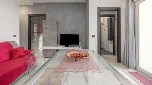A modern living room with a glass coffee table, a flat-screen TV, and a red sofa. - Apartment 'Lido Azzurro Sea Terra' with Mountain View, Wi-Fi and Air Conditioning (Carini)