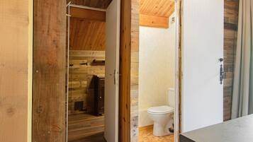 Een houten interieur met een houten deur die leidt naar een badkamer met toilet en douche.