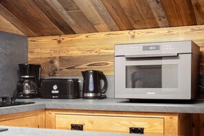 Una cocina con microondas incorporado, cafetera y jarra para café.