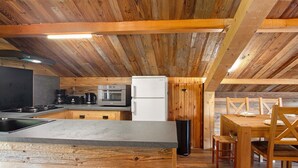 Cocina compacta con vigas de madera, una isla central y electrodomésticos modernos, incluyendo un microondas y un refrigerador.