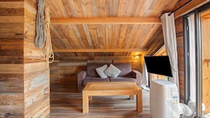 Interior acogedor de una cabaña con techo de madera, un sofá, una mesa y un televisor.
