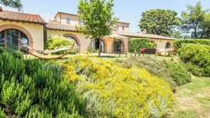 A Mediterranean-style villa with a garden featuring yellow flowers and a hammock. - Apartment with A/C, pool, WIFI, TV, patio, pets allowed, panoramic view, close to Montepulciano (Torrita Di Siena)