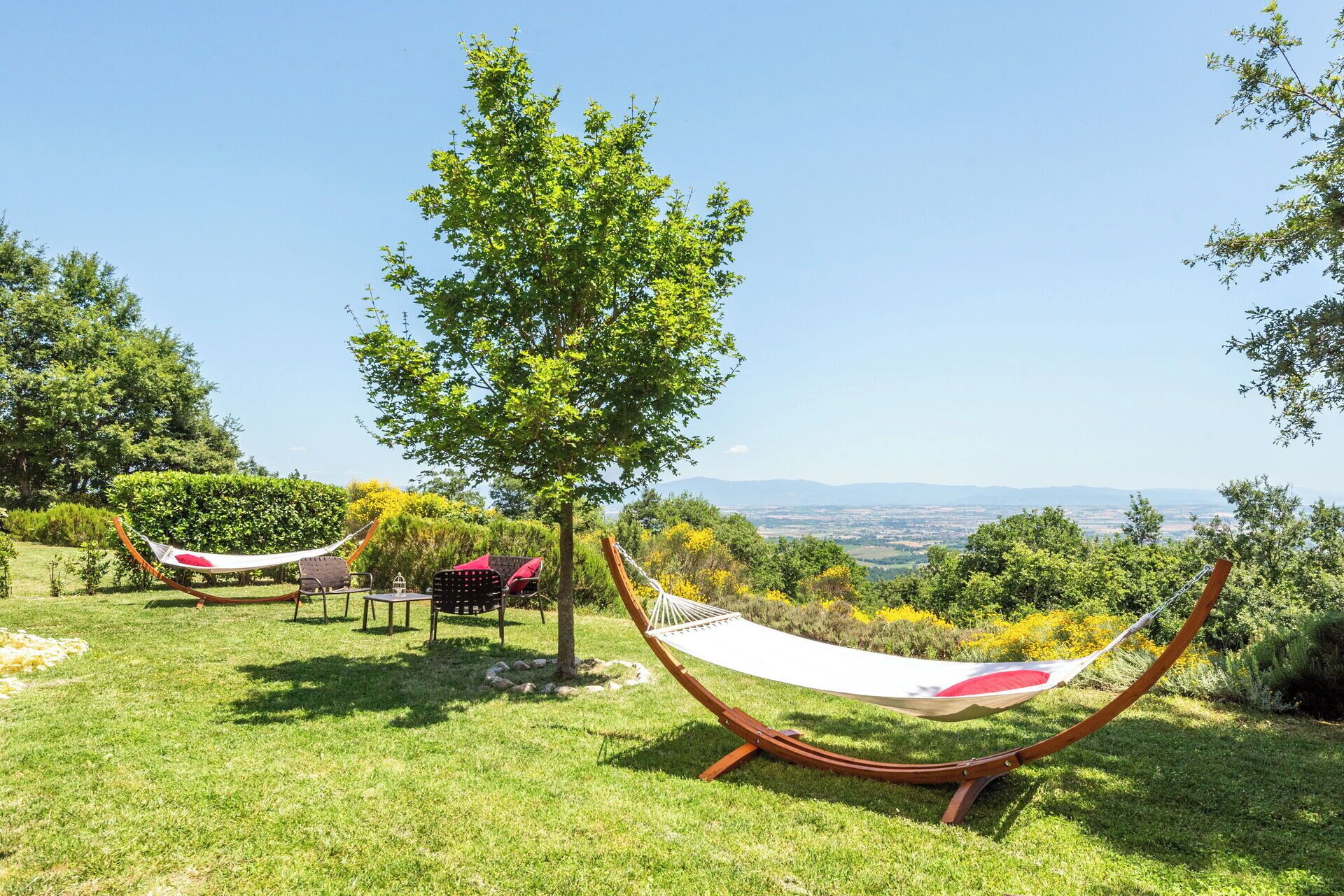A hammock chair in a grassy outdoor area with a view of distant hills.