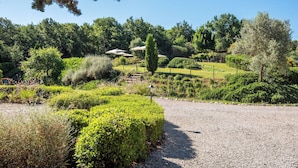 A landscaped garden with pathways, neatly trimmed hedges, and a variety of trees and shrubs. - Cosy apartment with WIFI, pool, A/C, TV, patio, pets allowed, panoramic view, close to Montepulciano (Torrita Di Siena)