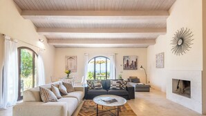 A spacious living room with a high ceiling, a fireplace, and a view of the outdoors through large windows. - Cosy apartment with WIFI, pool, A/C, TV, patio, pets allowed, panoramic view, close to Montepulciano (Torrita Di Siena)