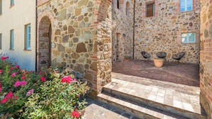A courtyard with stone walls, a brick floor, and a seating area with chairs. - Nice apartment with pool, A/C, WIFI, TV, patio, pets allowed, panoramic view, close to Montepulciano (Torrita Di Siena)
