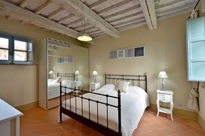 Une chambre à coucher avec un lit, des tables de chevet, un miroir et une fenêtre.