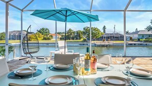 Un comedor con una mesa dispuesta para dos, un sillón colgante y vistas a un cuerpo de agua.