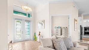 Amplia sala de estar con un sofá color beige, una mesa de comedor y una cocina con armarios blancos y un refrigerador.