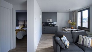 Een modern appartement met een woonkamer, een kitchenette en een slaapkamer.