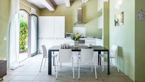 A modern kitchen with white cabinets, a dining table with chairs, and a view of the outdoors through a glass door. - Nice apartment with pool, WIFI, A/C, TV, terrace and pets allowed, close to Montepulciano (Torrita Di Siena)