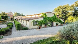 A traditional villa with a gravel driveway, a garden with neatly trimmed hedges, and a small outdoor seating area. - Nice apartment with pool, WIFI, A/C, TV, terrace and pets allowed, close to Montepulciano (Torrita Di Siena)