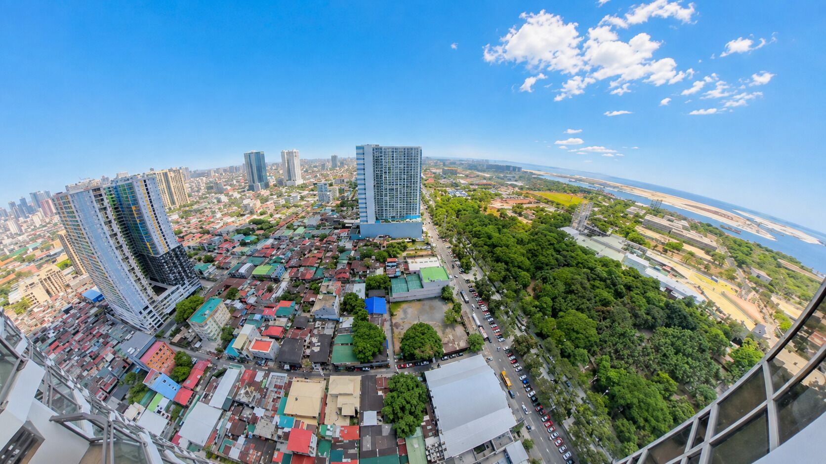 A panoramic view of a cityscape with high-rise buildings, a river, and a dense urban area with various buildings and greenery.