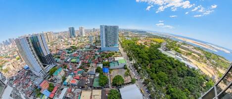 A panoramic view of a cityscape with high-rise buildings, a river, and a dense urban area with various buildings and greenery.