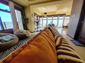 A modern living room with a sofa, a fan, and a view of the outdoors.