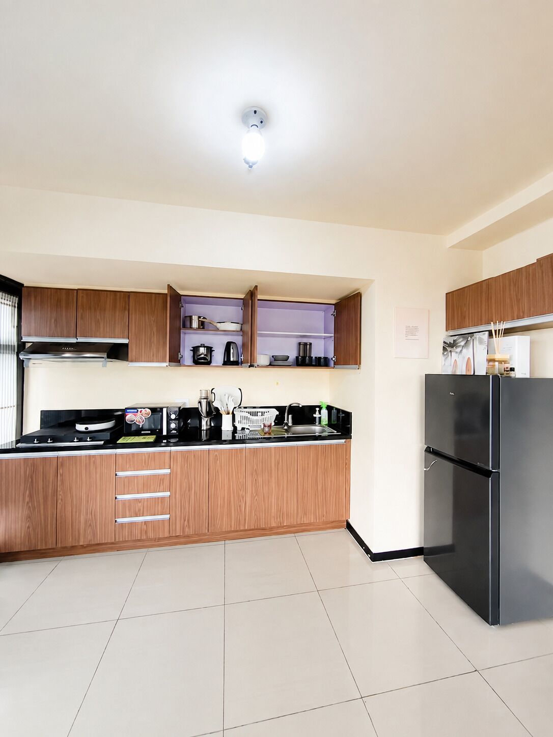 Una cocina moderna con armarios de madera, un refrigerador negro y una estufa a gas.