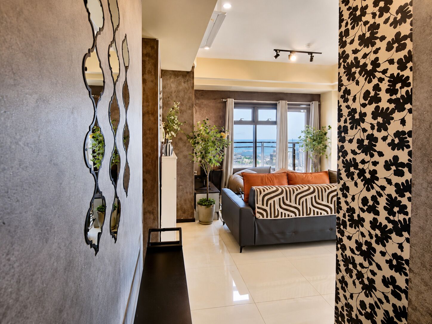 A modern living room with a sofa, a decorative wall piece, and a view of the city.
