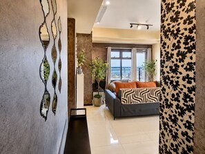 Un salon moderne avec un canapé, un élément décoratif mural et une vue sur la ville.