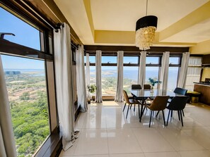 A dining area with a view of the landscape, large windows, and a chandelier.