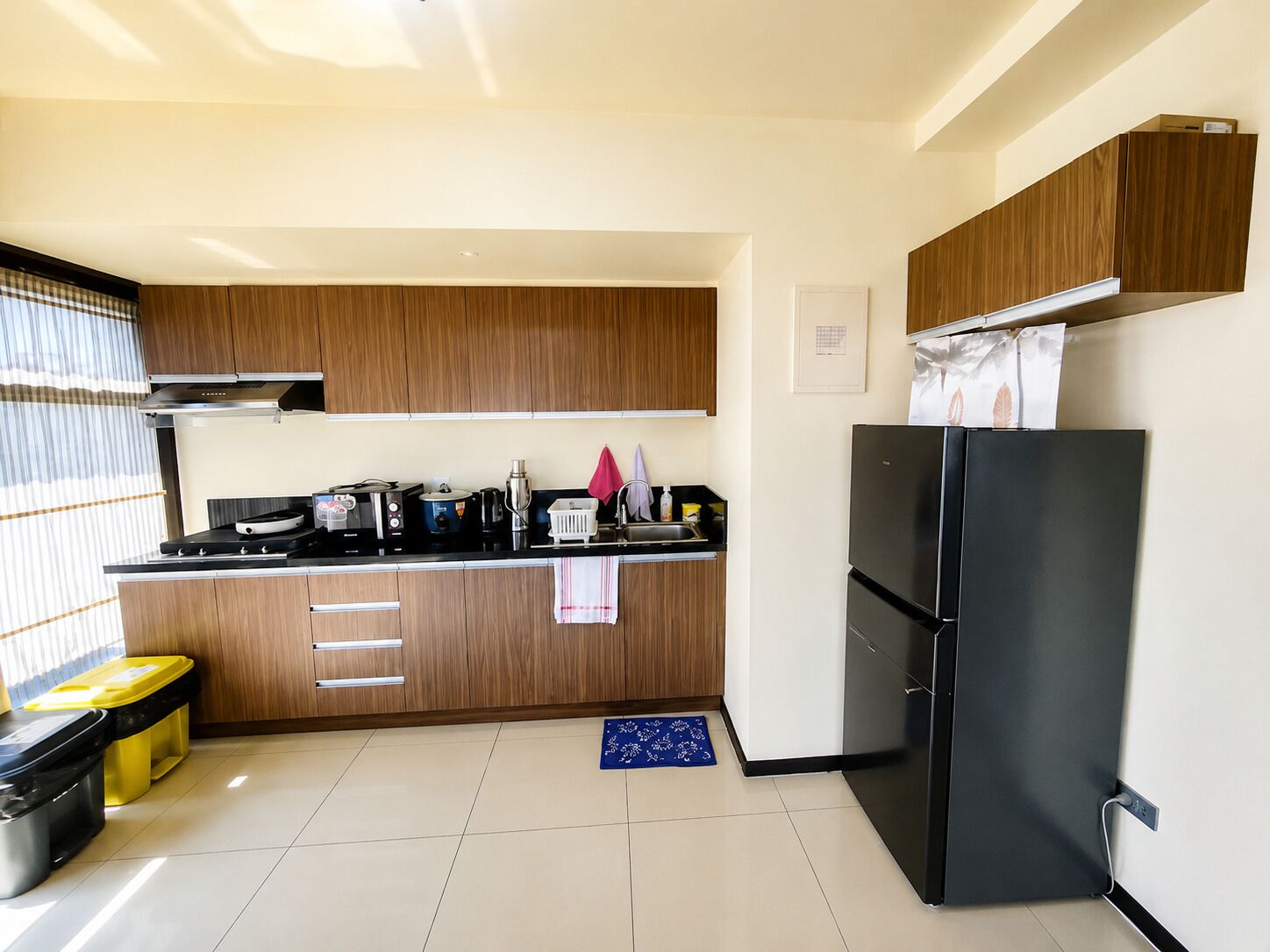 Eine moderne Küche mit Holzausstattung, einem schwarzen Kühlschrank und einer Arbeitsfläche mit verschiedenen Geräten.