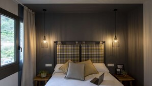 Un dormitorio moderno con una cama grande, dos mesitas de noche, un ordenador portátil y una ventana con cortinas.