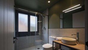 Un baño moderno con ducha envuelta en vidrio, inodoro y tocador con lavamanos.
