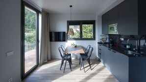 Una cocina moderna con comedor, ventanas amplias y vistas a zonas verdes.