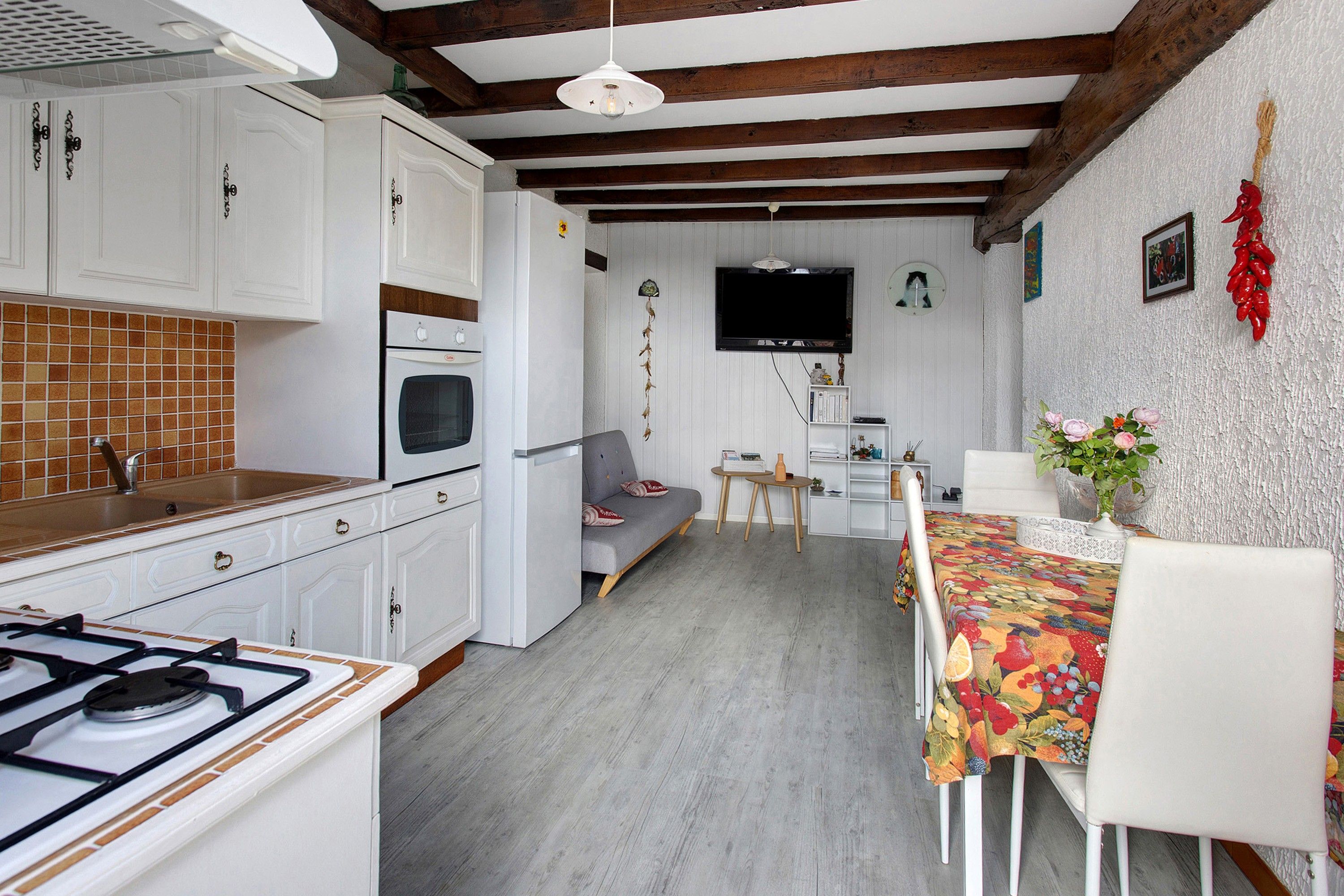 A compact kitchen with white cabinets, a gas stove, and a tiled backsplash.