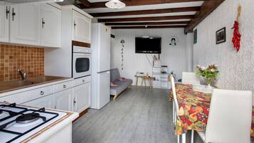 A compact kitchen with white cabinets, a gas stove, and a tiled backsplash.
