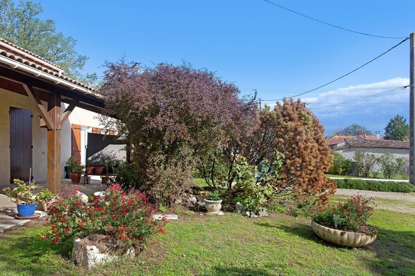 A residential property with a garden, a house with a tiled roof, and a clear sky.