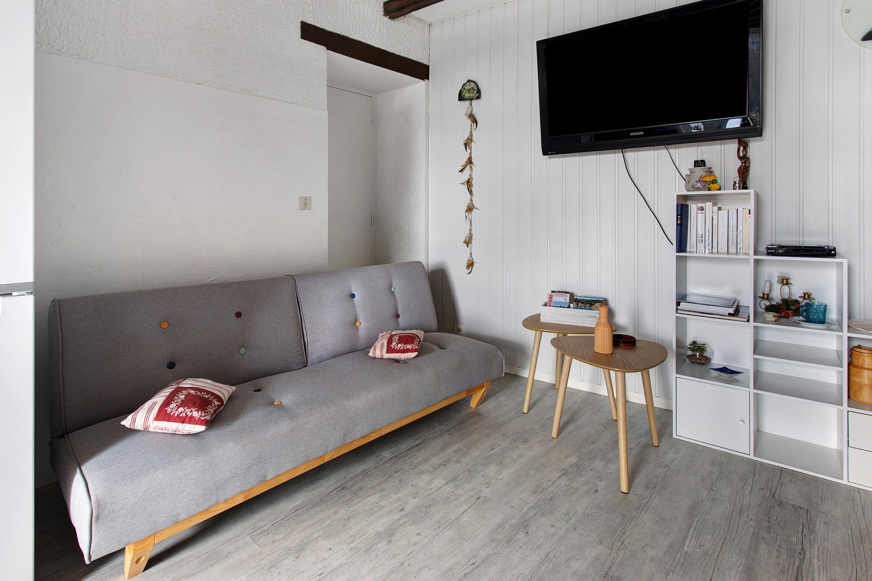 A living room with a grey sofa, a small round table, and a bookshelf.