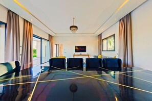 A spacious room with a large black table, two sofas, and a TV screen displaying 'NETFLIX'. - Spacious 5-bedroom villa in peaceful Marrakech-Safi with AC (Marrakech-Safi)