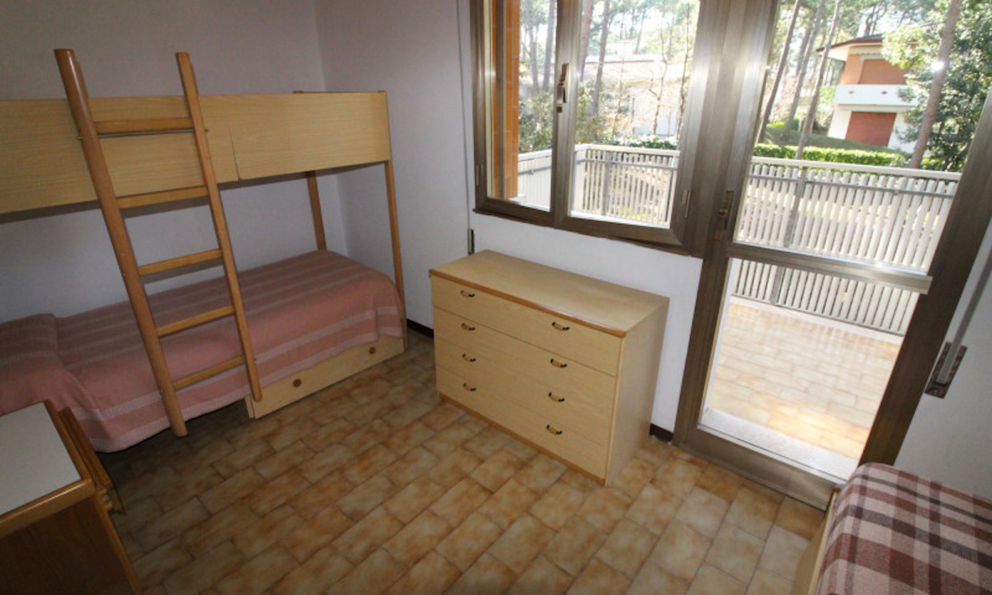 Une chambre avec un lit superposé, une commode en bois et une fenêtre.
