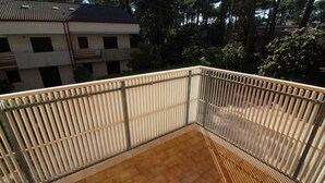 Un balcon doté d’un sol carrelé et d’une rambarde en métal.