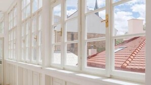 Un pasillo con ventanas amplias, paredes blancas y piso a cuadros.
