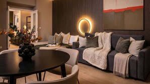 Un salón moderno con un sofá gris oscuro, una mesa de centro redonda y una lámpara circular fijada a la pared.