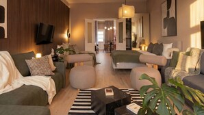 Una sala de estar moderna con un sofá, una mesa de centro y un televisor. Se observa un comedor al fondo.