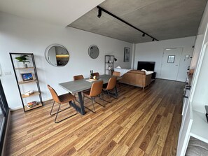 Ein modernes Wohnzimmer mit Essbereich, Holzboden und einer Couch.